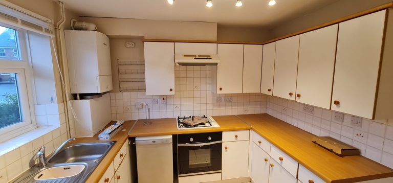 Modern kitchen with white cabinets, wooden countertop, and stainless steel appliances.
