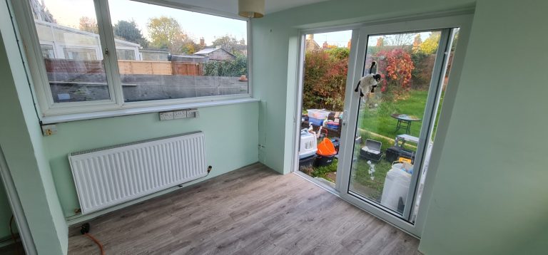 Bright room with green walls, a radiator, and large sliding doors opening to a garden.