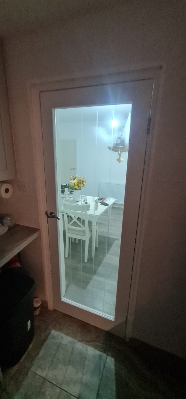 Glass door leading to a bright dining area with a table and chairs.